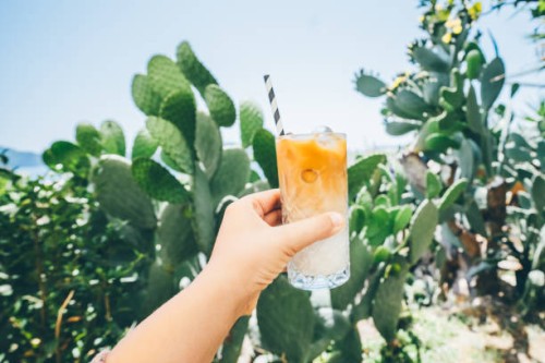 iced latte in glass with straw in woman hand. - junk food stock pictures, royalty-free photos & images