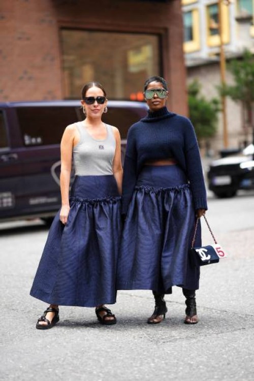 Idalia Salsamendi wears black sunglasses, gold earrings, a pale gray tank-top from Loewe, a navy blue denim high waist long skirt, a silver watch,...