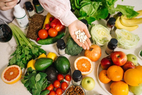 in the dietitian's office, the table is set with vegetables, fruits, nuts, bread, herbs, capsules of drugs in the palm - food stock pictures, royalty-free photos & images