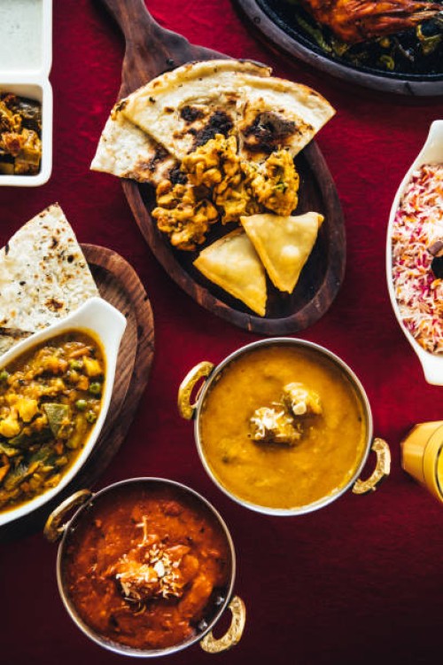 indian feast with butter chicken, chicken tandoori, lamb curry, vegetable curry, samosas, pakoras, bhajis, naan bread and basmati rice on a table. north indian food - food stock pictures, royalty-free photos & images