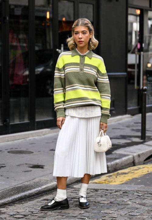 Ines Isaias is seen wearing a green striped Lacoste sweater, white shirt, white panel skirt, white socks, black shoes and Lacoste white bag outside...