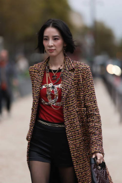 Irene Kim is seen outside Chanel show wearing gold Chanel necklaces, yellowish tweed Chanel coat, black leather shorts, golden Chanel belt, black...
