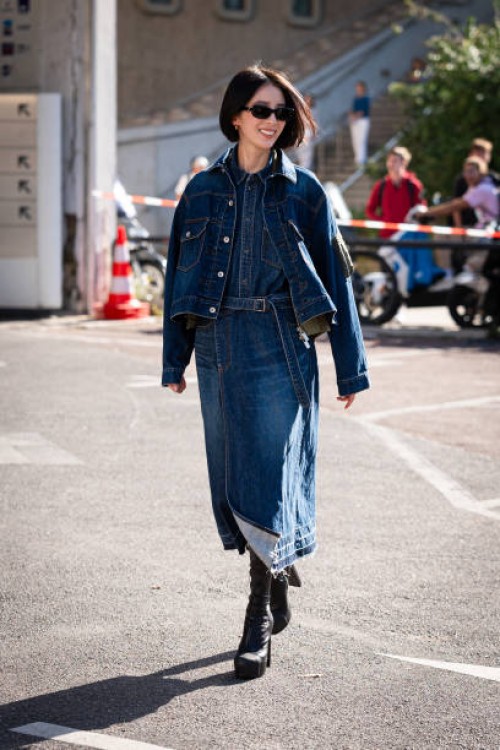 Irene Kim wears a blue denim shirt, blue denim jacket, denim midi skirt and black boots, outside Sacai, during the Womenswear Spring/Summer 2024 as...