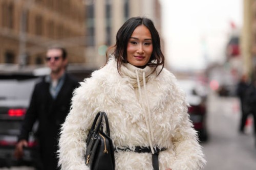 Isabel Tan wears cream Michael Kors hoodie, cream faux fur oversized Michael Kors coat, shiny black Michael Kors leather belt, shiny black Michael...