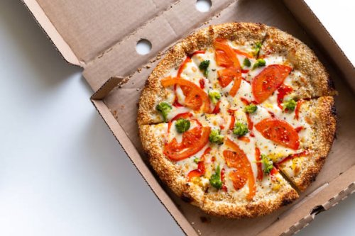 italian pizza in a pizza box and for delivery, on a white background or table. pizza margarita with tomatoes and cheese and broccoli, without meat. the concept of vegetarian food, fast junk food. delivery to your home or work