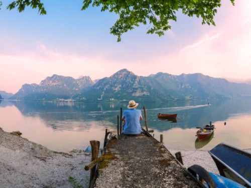 italy, lombardy, back view of man sitting on jetty at lake idro at morning twilight - travel stock pictures, royalty-free photos & images