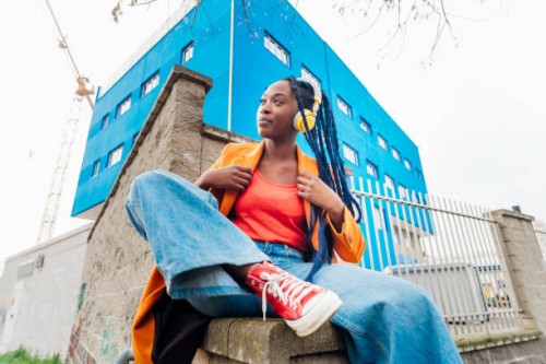italy, milan, portrait of woman in orange coat against rusty metal fence - fashion stock pictures, royalty-free photos & images
