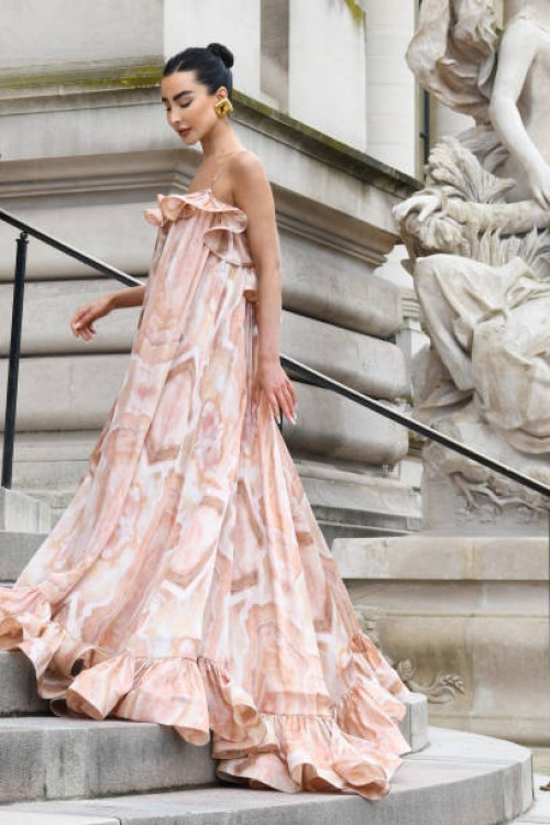 Izabelle Angus wears white and silverleather heeled sandals, a pink floral printed ruffles long maxi dress and gold earrings outside Zimmermann...