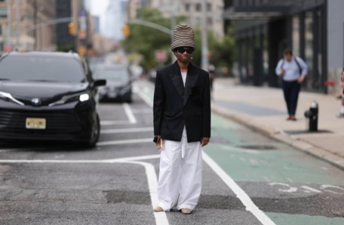 Jalil Johnson is seen wearing a large striped hat in black and natural hemp, from Esenshel, black butterfly-shaped sunglasses, dangling earrings with...