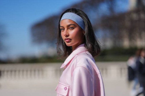 Jamilla Strand wears light blue denim jean headband, gold earrings, light pink short sleeve half zipped oversized Casablanca shirt, outside...
