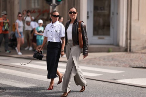 Janka Polliani is seen wearing black narrow cat-eye sunglasses from Balenciaga, several silver hoop earrings and stud earrings, a white cropped shirt...