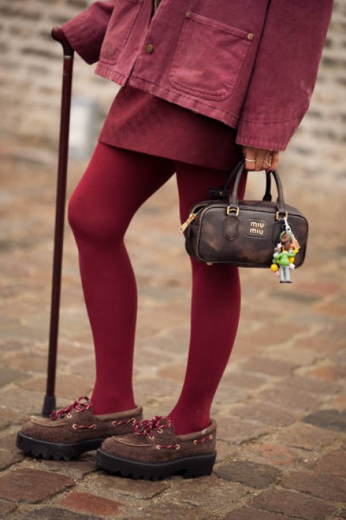 Janka Polliani wears burgundy jacket, burgundy skirt, burgundy tights, brown shoes, brown Miu Miu bag outside the Munthe fashion show during the...