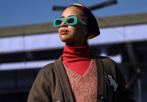 Jasmin Savoy Brown is seen wearing a brown sweater vest, red turtle neck, blue pants, gold boots, Coach bag and lime green sunglasses outside the...