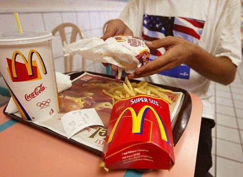 Jeff Baughman unwraps his Double Quarterpounder with cheese and a Super Fries and a Super Coke on July 18, 2002 at a McDonalds in Miami Beach,...