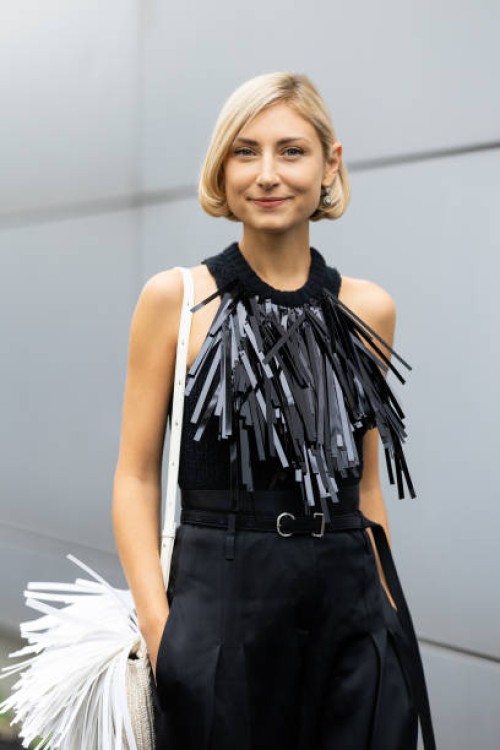 Jenny Walton is seen wearing a white leather bag with fringe, a black leather belt, black high waist trousers and a black knitted tank top...