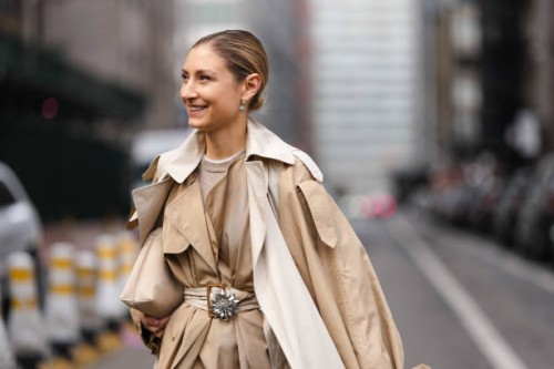 Jenny Walton wears silver earrings, light brown shirt, tan beige loop belted Celine trench coat, tan beige leather clutch bag, outside Altuzarra,...