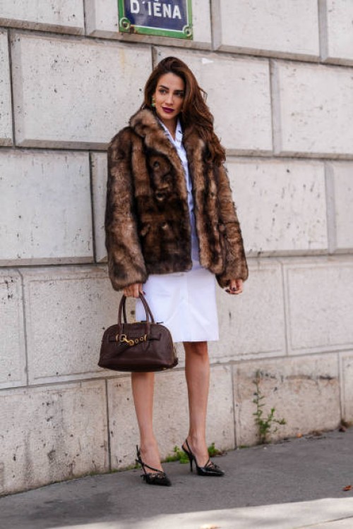 Jessica Kahawaty wears white buttoned up midi dress, faux fur coat, dark brown leather bag, black pointed toe slingback heels, outside Miu Miu,...