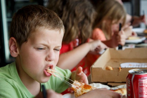 Joe Kendy IV bites into a piece of pizza at Pizza L'Vino, a pizza restaurant that offers home delivery and takeout for pizza, beer and wine, Friday,...