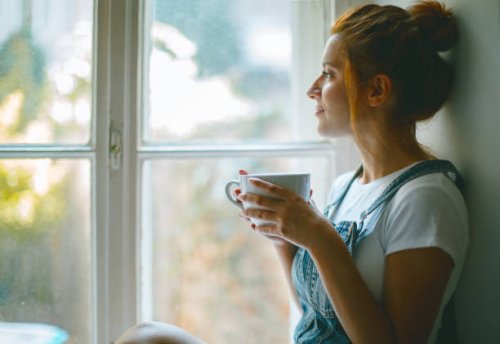 jonge mooie vrouw is op zoek door het raam en het drinken van koffie in de ochtend - coffee stockfoto's en -beelden