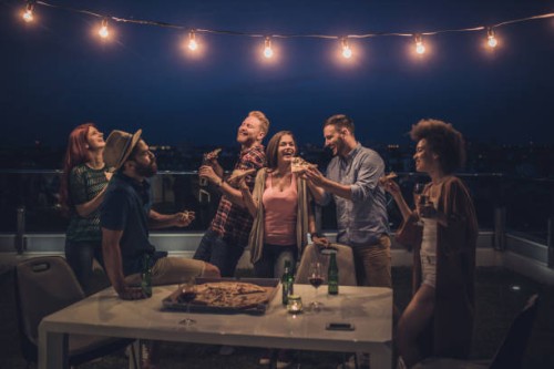 joyful friends having a dinner party during the night on a terrace. - junk food stock pictures, royalty-free photos & images