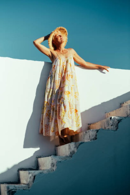 joyful woman in a flowing summer dress and straw hat, soaking in the sunlight on a white mediterranean-style staircase. - fashion stock pictures, royalty-free photos & images