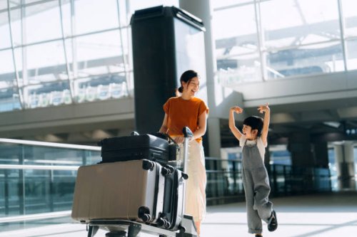 joyful young asian mother and little daughter travelling together, they are pushing a luggage trolley with suitcases at airport terminal. ready for a trip. travel and vacation concept - travel stockfoto's en -beelden