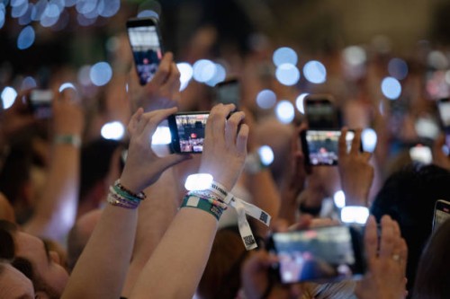 July 2024, North Rhine-Westphalia, Gelsenkirchen: Spectators film with their smartphones during singer Taylor Swift's concert in the Veltins Arena....