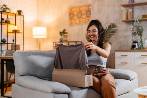junge frau packt ein paket mit einem neuen hemd aus - fashion stock-fotos und bilder