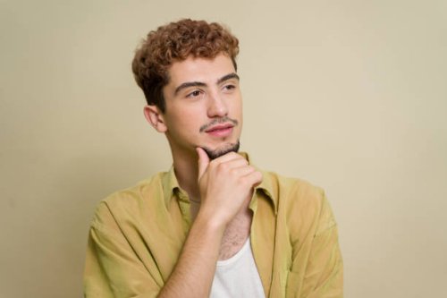 junger mann mit lockigem haar, tief in gedanken versunken - hairstyle stock-fotos und bilder