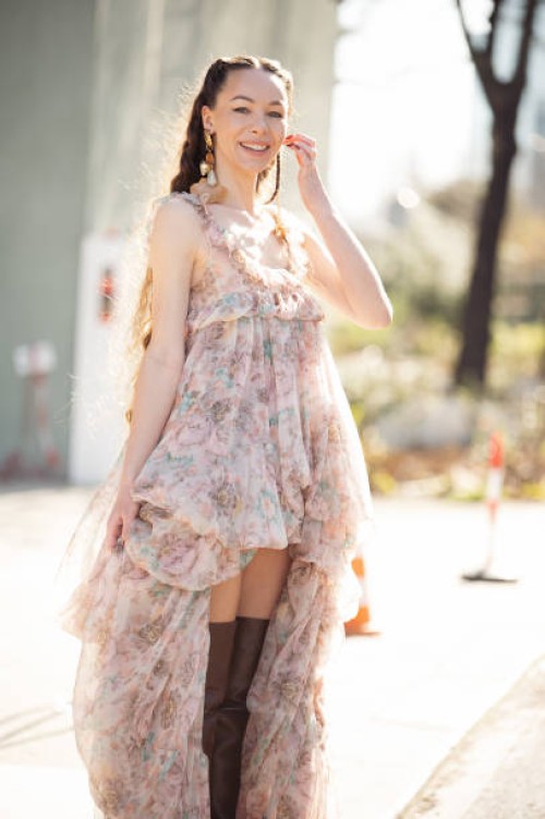 Jurga Fulti wears short in front and long in the back, light brown and pink dress and long brown leather boots outside the Chloe fashion show during...