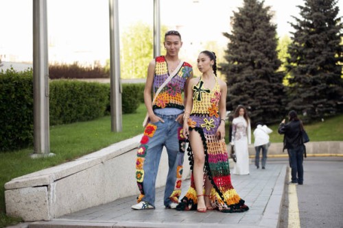 Kanybayev Assylkhan wears blue jeans with knitted colourful details and matching colors knitted vest and Marzhan Sharipova wears long colourful...