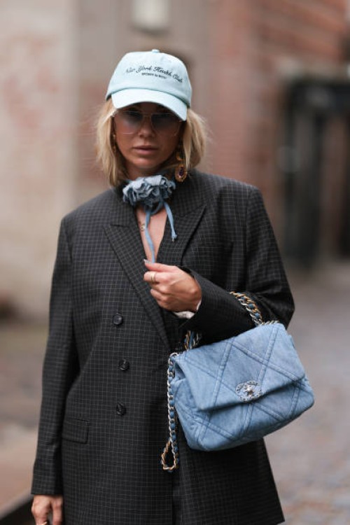 Karin Teigl seen wearing Munthe grey checked blazer jacket with matching suit pants, Sporty & Rich light blue cap, gold pendant earrings, Andy Wolf...