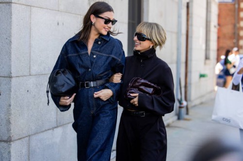 Kate Barlett wears denim shirt, jeans, black bag & Izzi Allain wears burgundy bag, jacket, pants outside Cos during New York Fashion Week on...