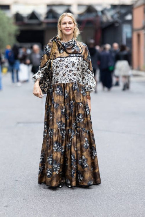 Kelly Rutherford is seen wearing silver maryjane pointy shoes, a brown leather watch, a beige, white and blue floral printed long-sleeved long dress...