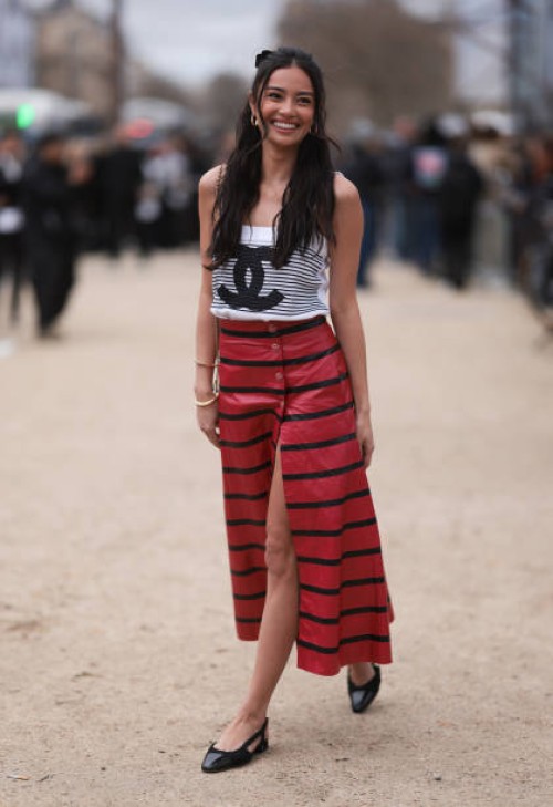 Kelsey Merritt seen wearing a black and white striped Chanel top, black and red striped long skirt, black Chanel ballerinas and a mini brown and...