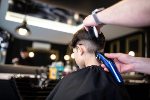 kleiner 7-jähriger junge geht in einen friseursalon, um einen modernen haarschnitt zu bekommen, rückansicht rasieren - hairstyle stock-fotos und bilder