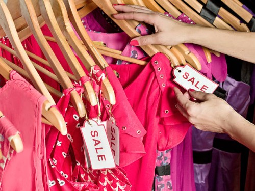 lady picking out dresses with a sale tag on it - fashion stock pictures, royalty-free photos & images