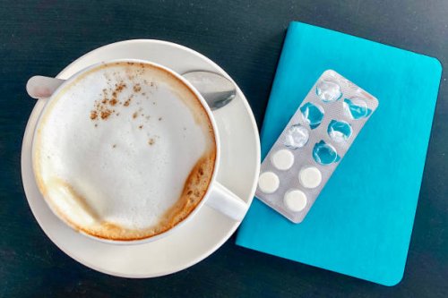 large cappuccino cup next white pills and blue diary - coffee stockfoto's en -beelden