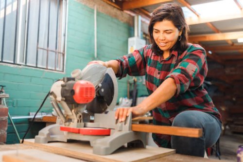 latin woodworker woman using a miter saw on a wooden plank, in her home workshop. - home decoration stock pictures, royalty-free photos & images