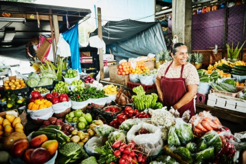 laughing female produce vendor working at stand in marketplace - food stock pictures, royalty-free photos & images