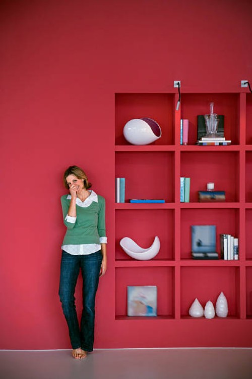 laughing woman leaning against red wall - home decoration stock pictures, royalty-free photos & images