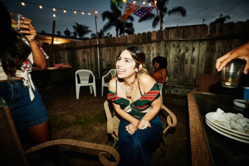laughing woman sitting in backyard with friends during party on summer evening - garden decoration stock pictures, royalty-free photos & images