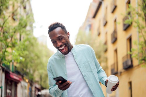 laughing young man with reusable cup using smart phone at street - junk food stock pictures, royalty-free photos & images