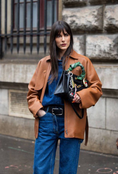 Leia Sfez wears black bag, brown jacket, denim shirt, belt, jeans outside Hermes during the Womenswear Fall/Winter 2024/2025 as part of Paris Fashion...