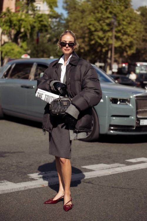 Leonie Hanne wears dark geri skirt, white shirt oversized jacket and black bag outside the Miu Miu show during Womenswear Spring/Summer 2025 as part...