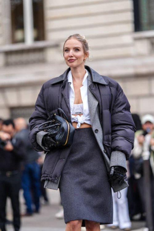 Leonie Hanne wears white Miu Miu bralette, white buttoned up long sleeve tied shirt, dark gray Miu Miu blazer jacket, black high waisted Miu Miu over...