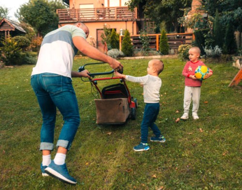 les enfants jouent dans la cour pendant que papa tond l’herbe - garden decoration photos et images de collection