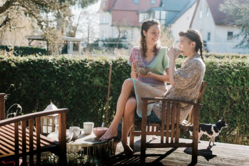 lesbian couple drinking coffee on decking in their garden - garden decoration photos et images de collection