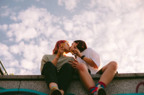lesbian couple kissing while sitting in the city during summer - fashion stock pictures, royalty-free photos & images