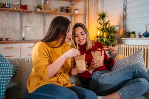 lesbian couple relaxing at home and eating pasta - junk food stock pictures, royalty-free photos & images